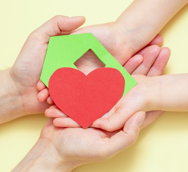 hands_holds_green_paper_house_with_red_heart